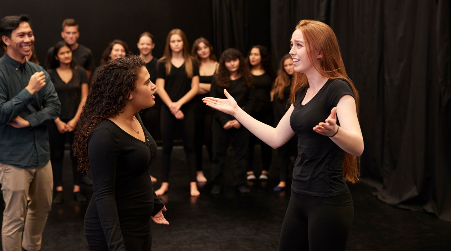 Deux participants à un atelier de comédie à Paris en plein exercice d'improvisation face à face, sourires et concentration mélangés